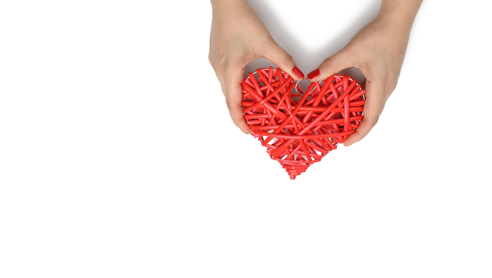 Two female hands hold a red wicker heart on a white background, the concept of gratitude, kindness